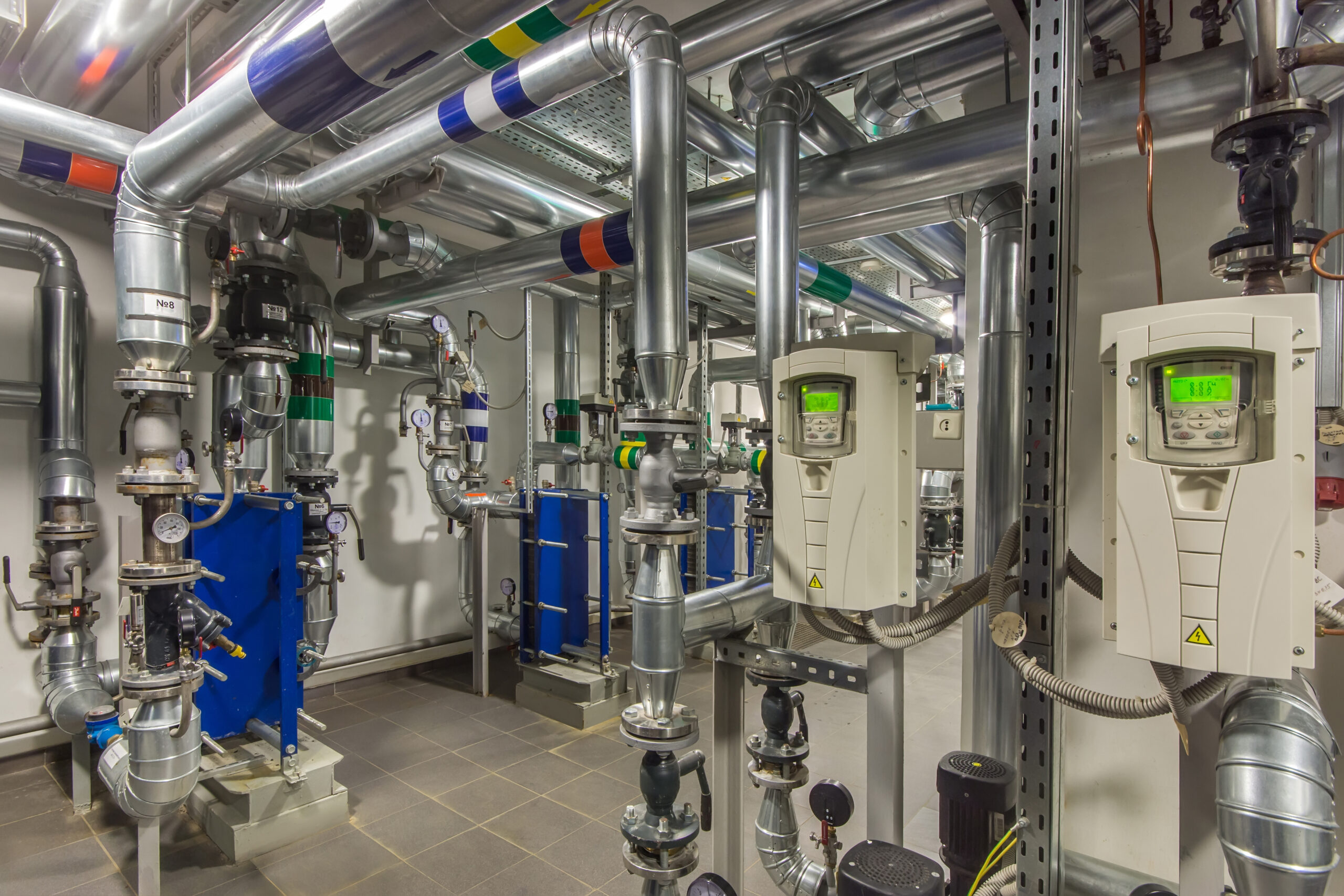 Commercial building plant room showing mechanical pipework, heat exchangers and building controls — KJ Tait