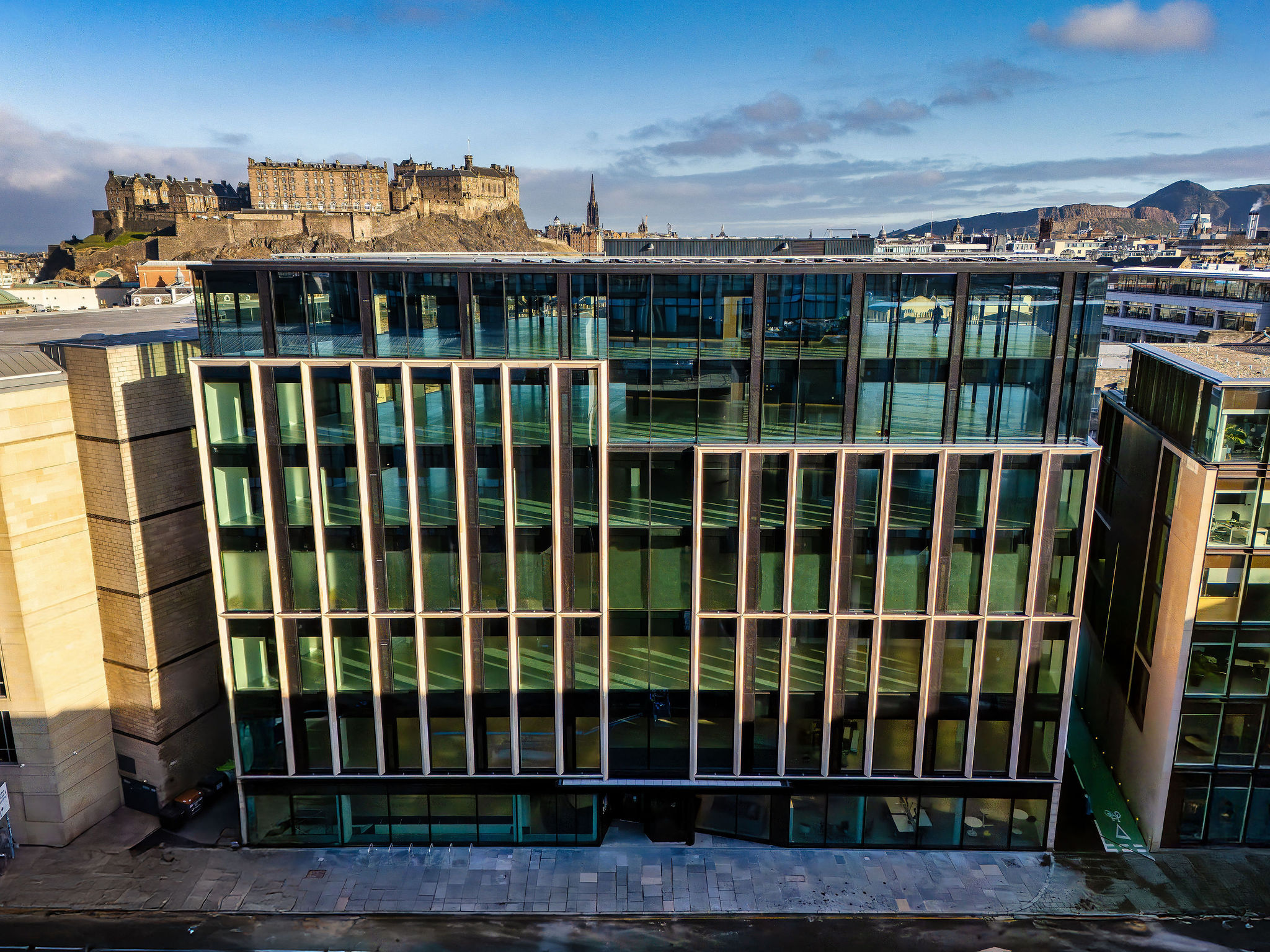 Modern glass office building in Edinburgh with Edinburgh Castle in background
