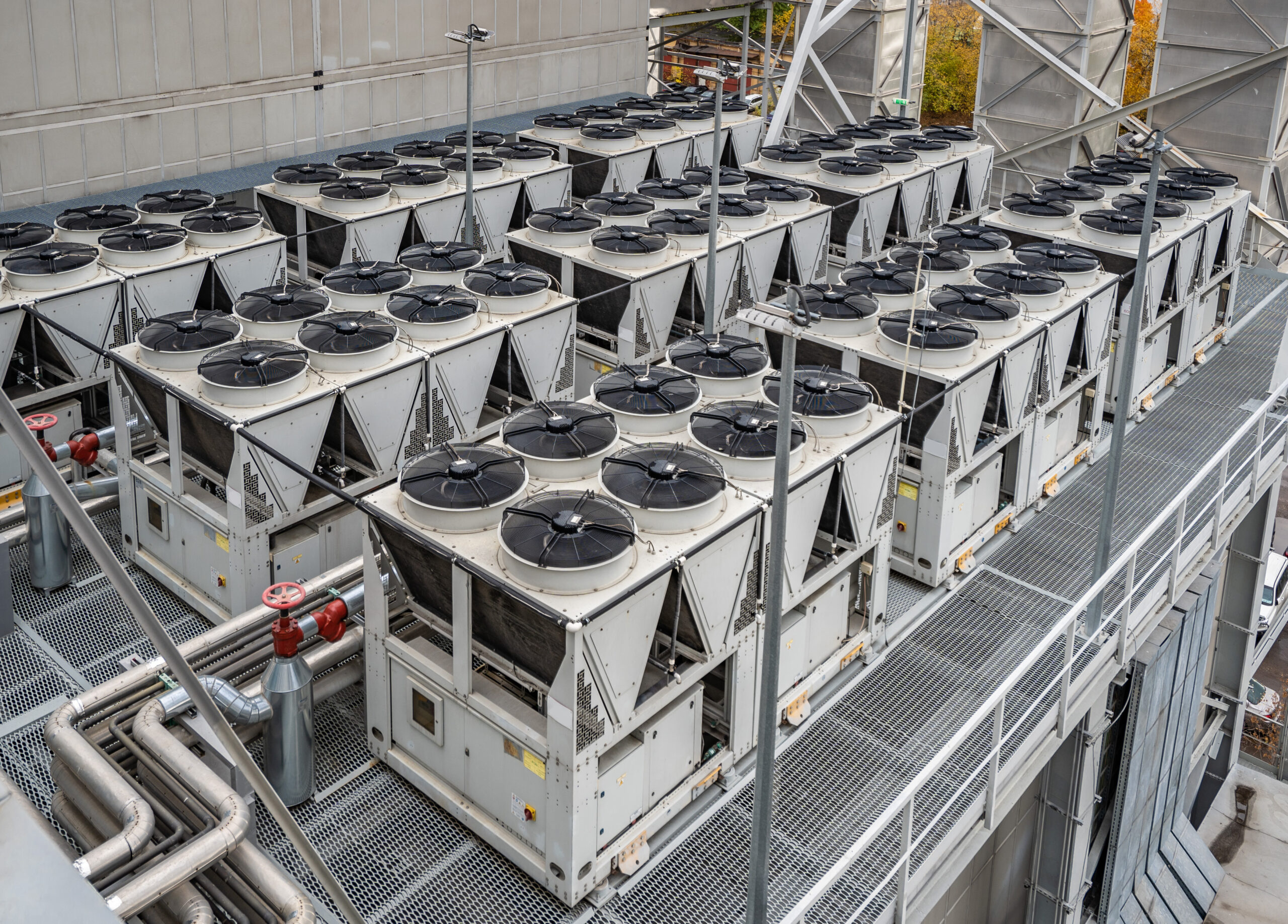 Bank of commercial air cooled chillers on a rooftop plant deck, the type of cooling equipment assessed during a TM44 air conditioning inspection.
