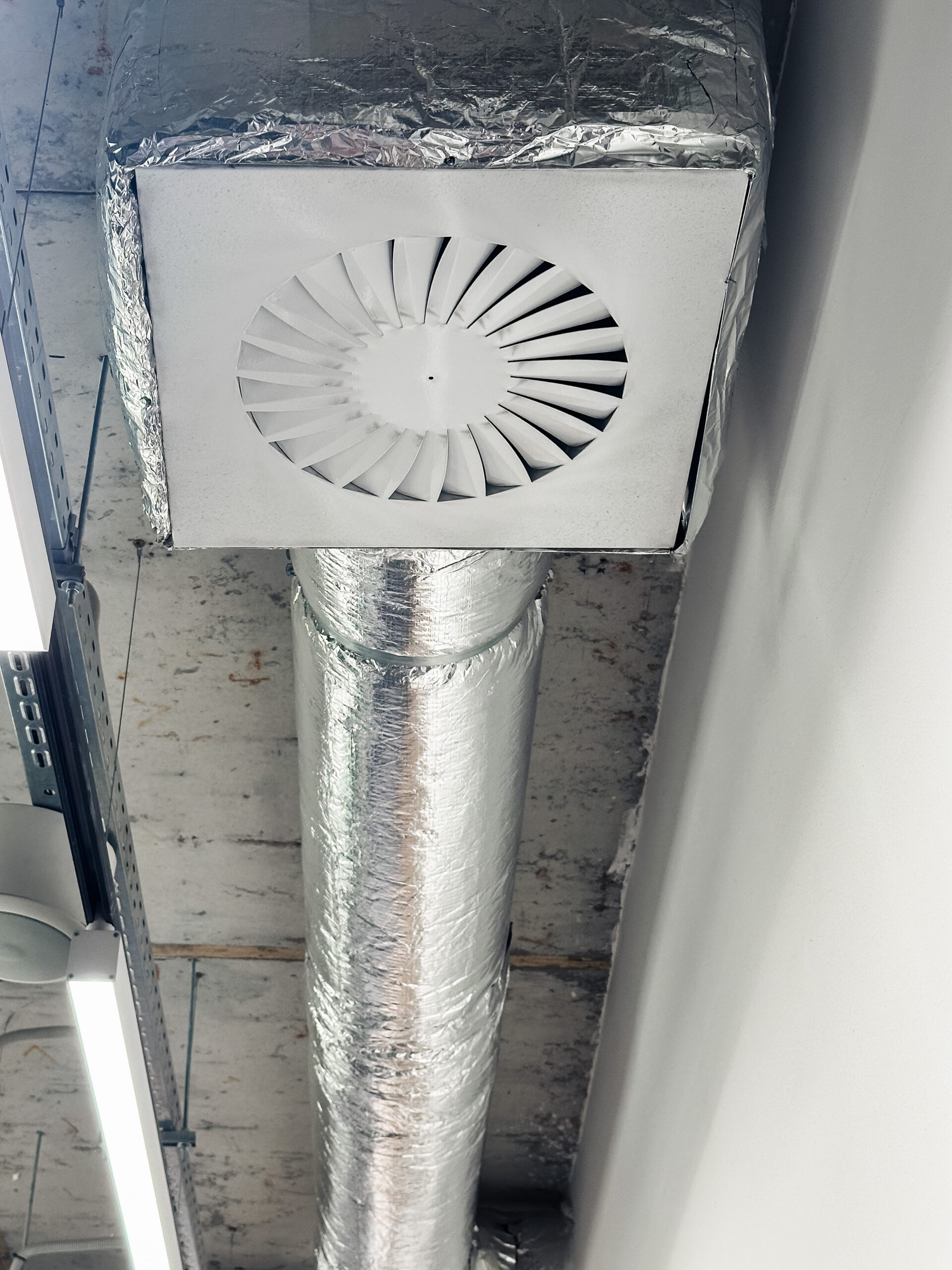Ceiling mounted swirl diffuser and insulated flexible ductwork serving a commercial air conditioning system, assessed during a TM44 air conditioning inspection.