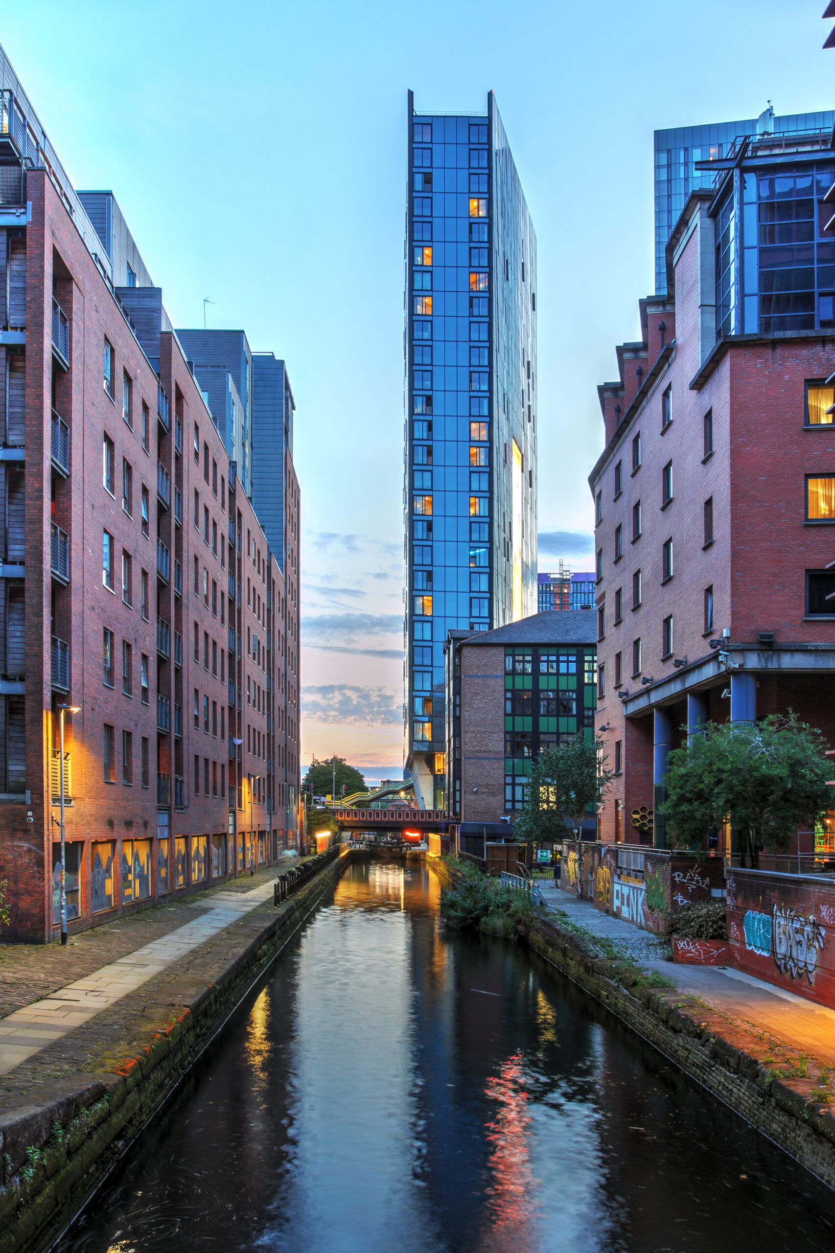 Urban canal in Manchester with modern and historic buildings at dusk